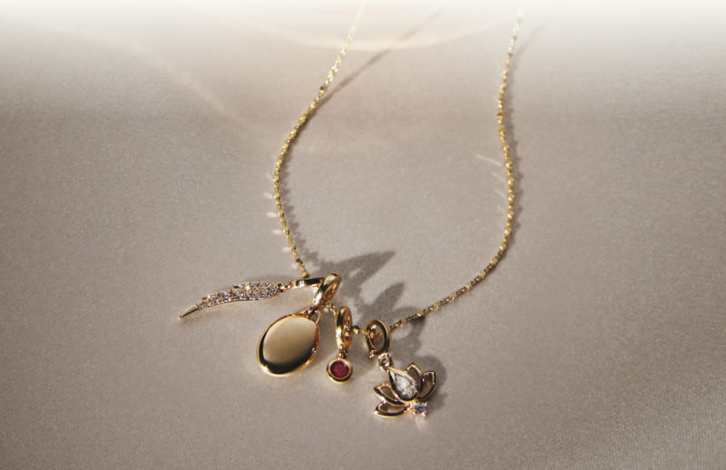Display of gold necklace with a variety of playful charms.