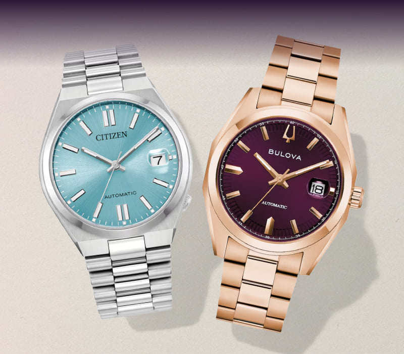 A watch with a silver band and a blue dial next to a watch with a rose-tone band and a purple dial.
