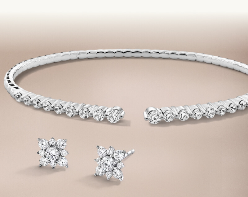 A diamond bangle bracelet, paired with clustered  flower-shaped diamond studs. 