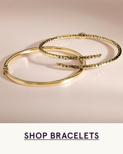 Two stacked gold thin bangle bracelets. Click here to shop bracelets