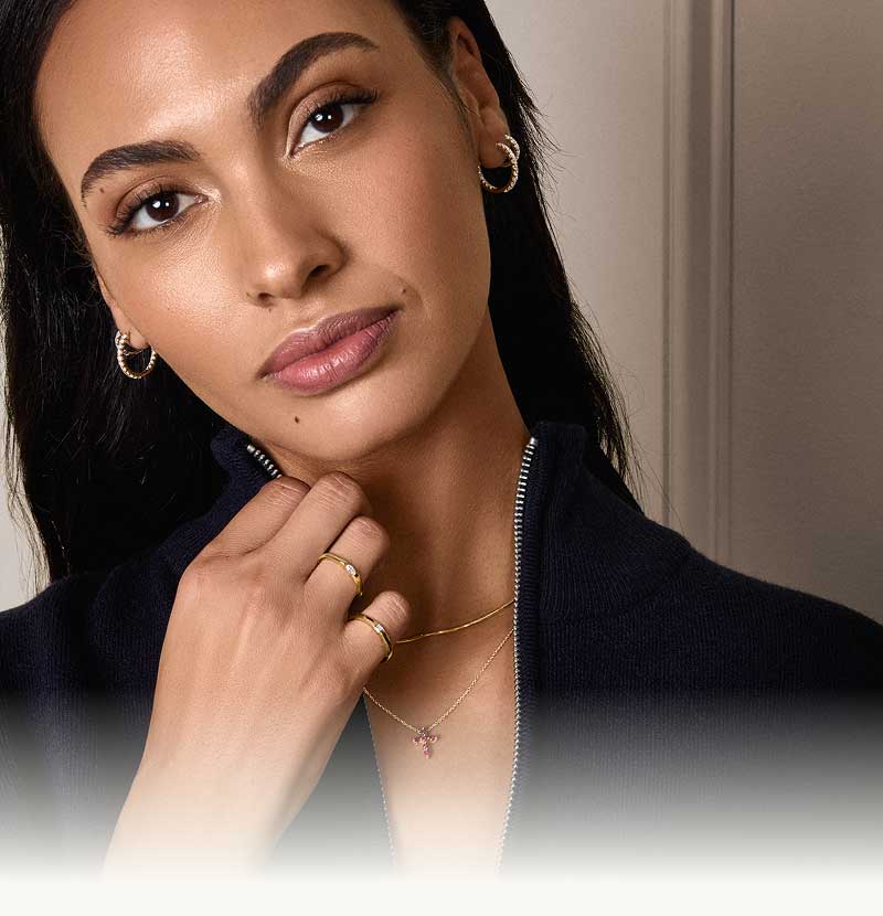 Model wearing dainty gold jewelry. 