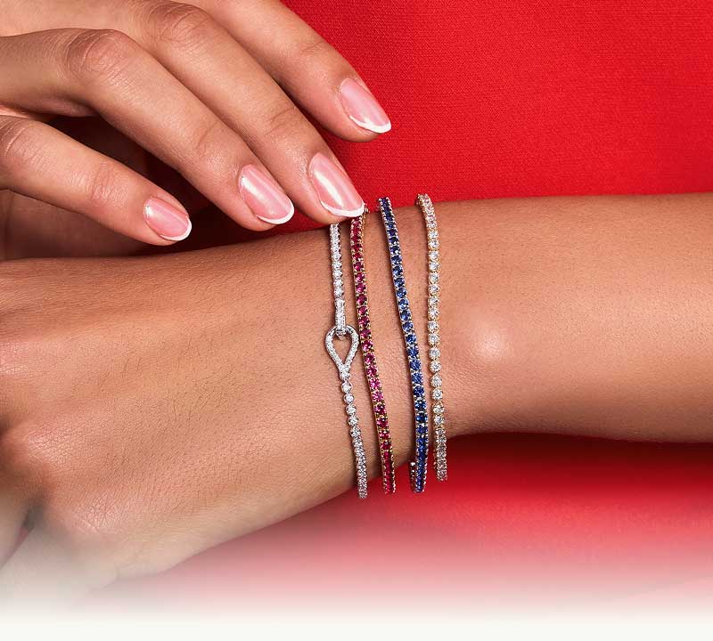 Focus on model’s wrist wearing four different color tennis bracelets.