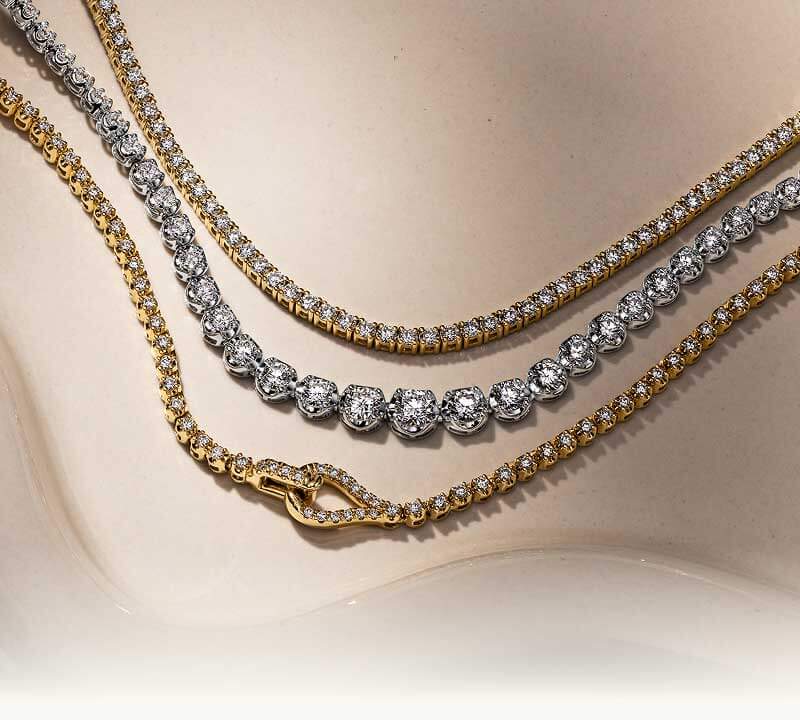 A styled arrangement of layered tennis-style necklaces, with different metal settings.