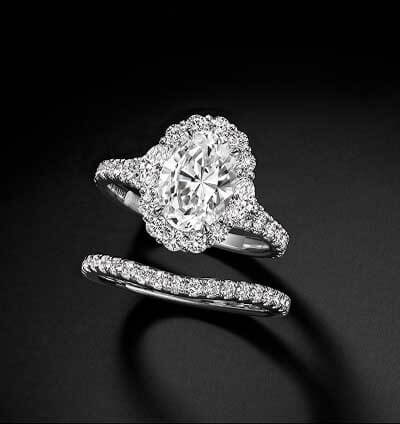 An oval-cut center stone surrounded by smaller pavé diamonds, paired with a matching diamond band.