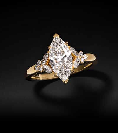 Warm gold ring with marquise center stone, with smaller diamond details around big stone.