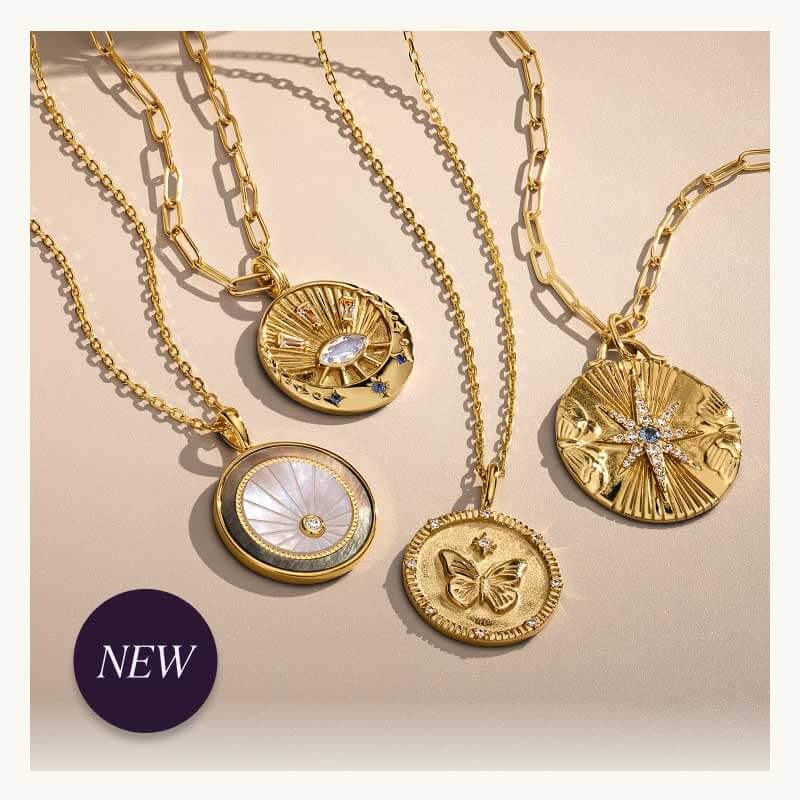Badge reads ‘NEW.’ Four diverse gold chain necklaces  with pendants designed with unique engravings & stones.