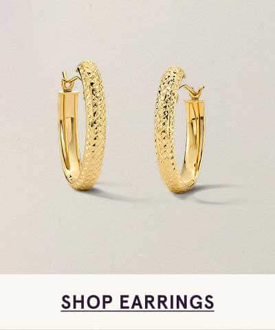 Pair of textured, golden huggie-like hoops. Click here to shop earrings
